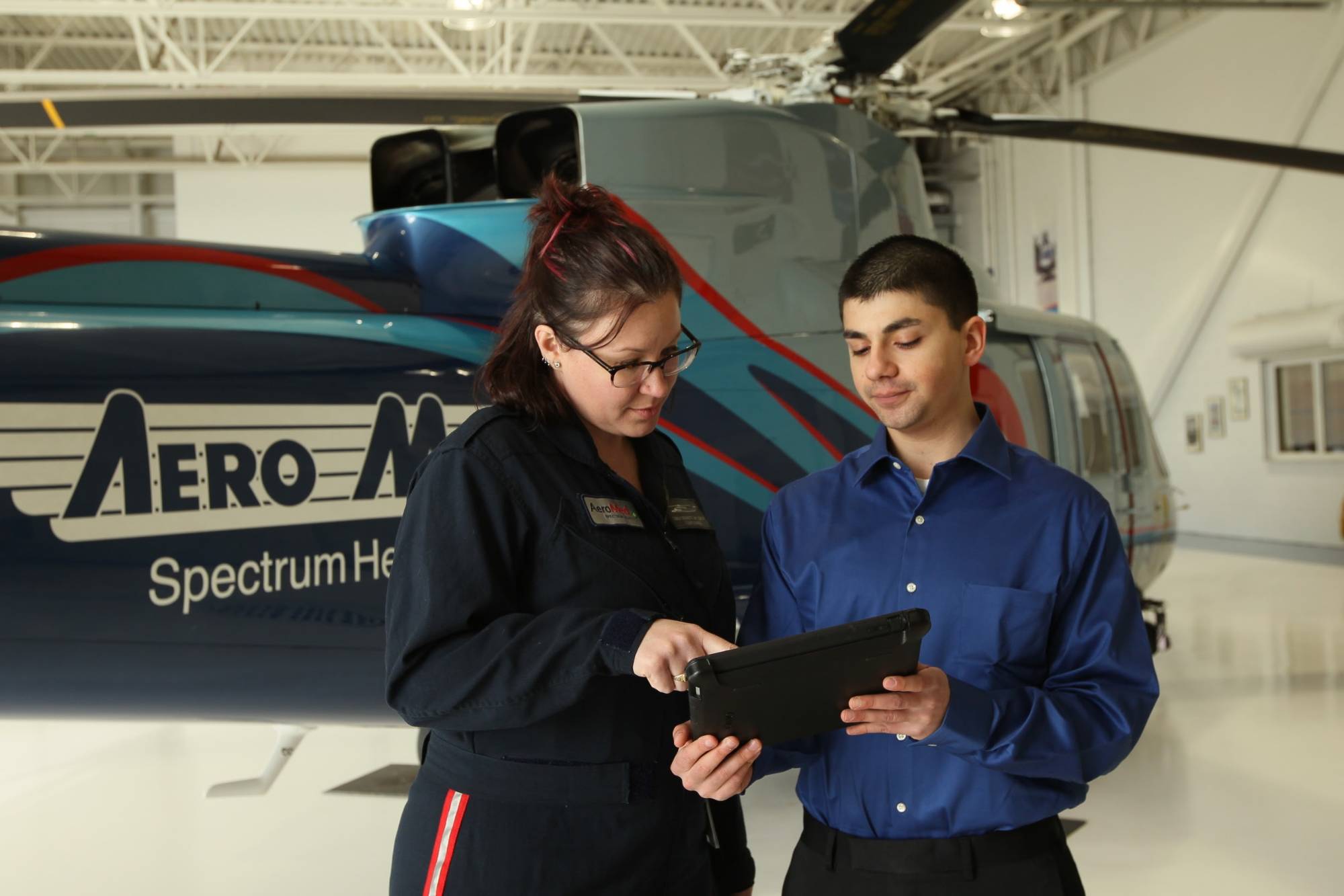 2 people looking at an iPad standing in front of a medical helicopter